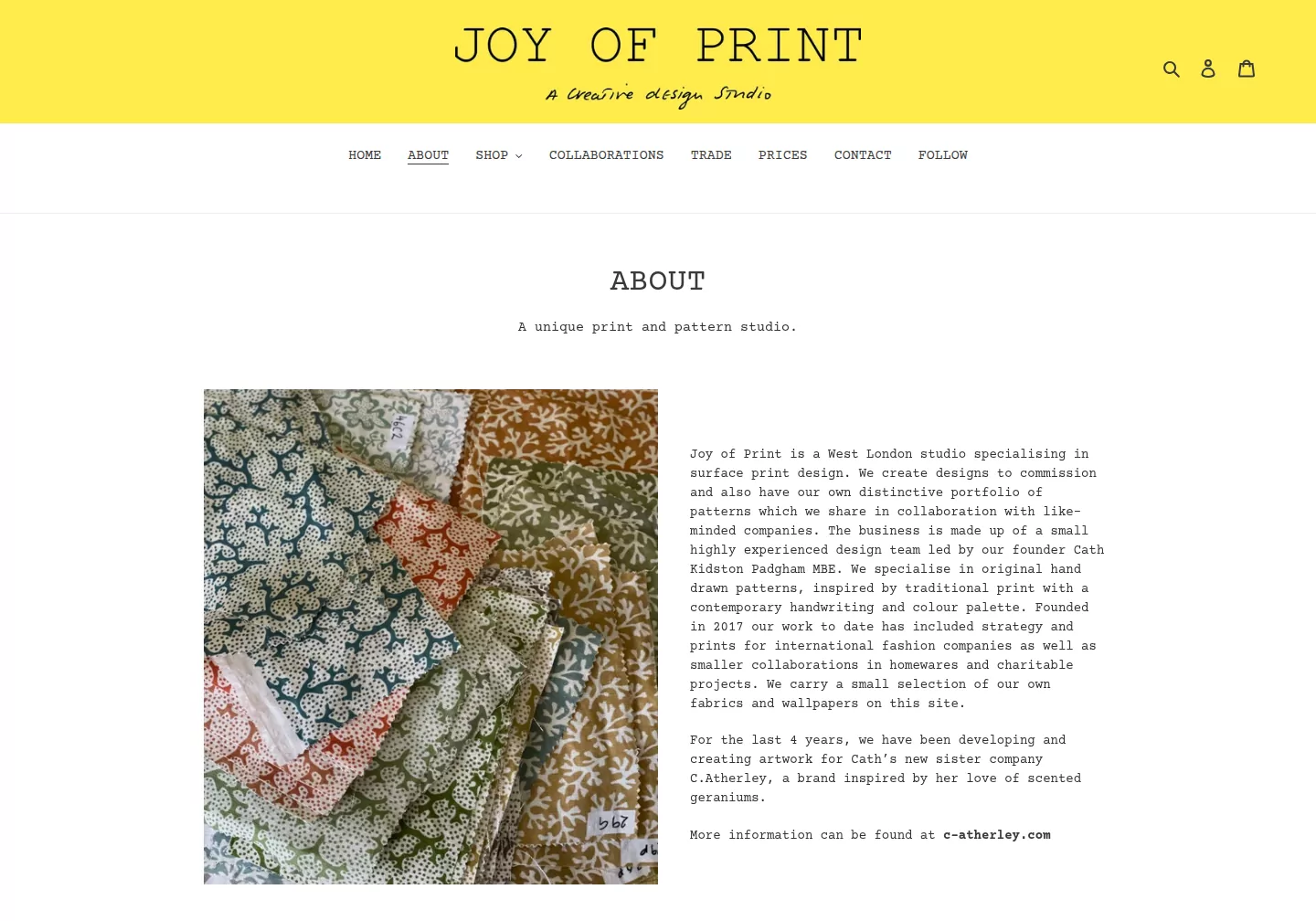 About page beside a pile of printed fabrics